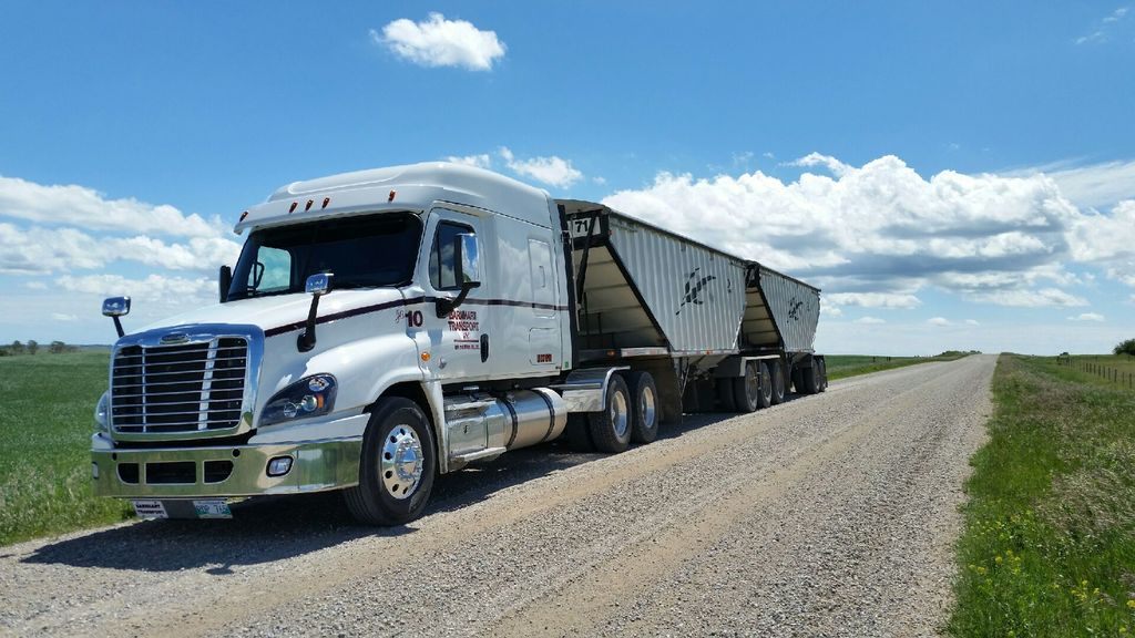 Barnhart Transport Freightliner double trailer hauling grain across a Prairie highway