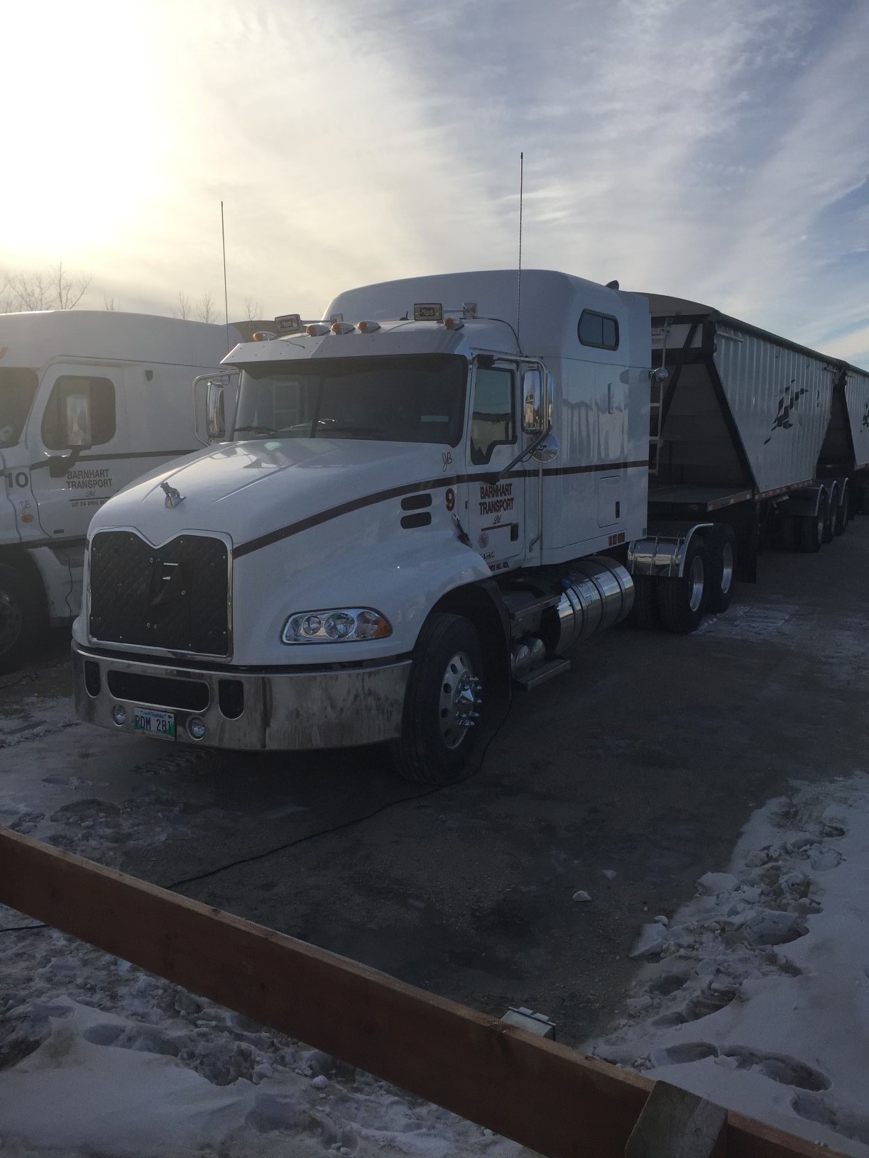 Barnhart Transport Mack truck parked in a snowy yard at sunrise, showing all-weather reliability